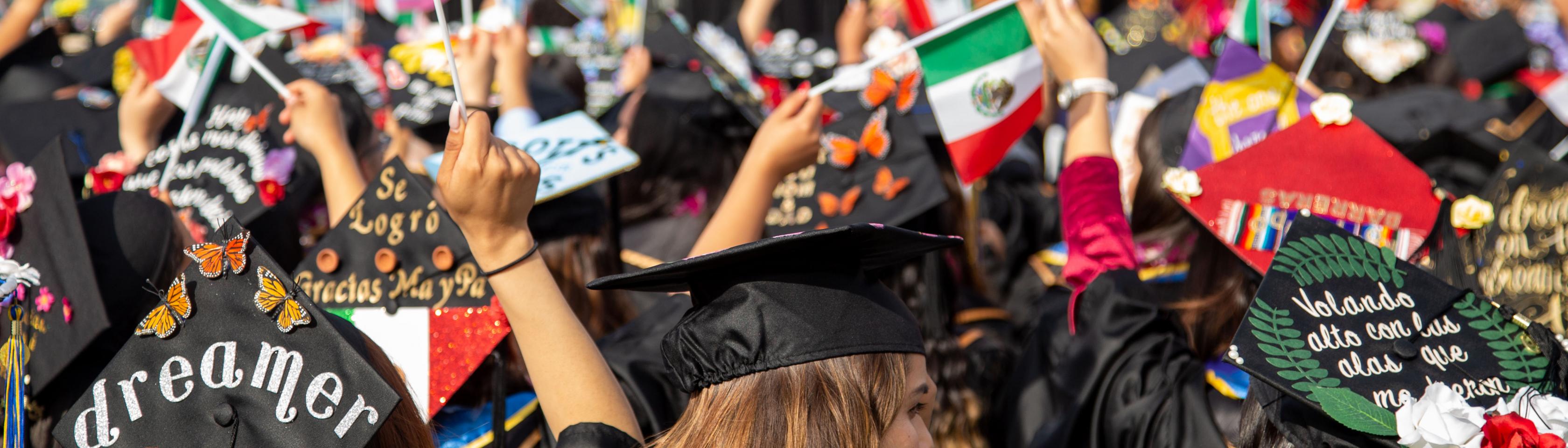 behind the head image of students dressed in decorative graduation garb waving flags of Mexico